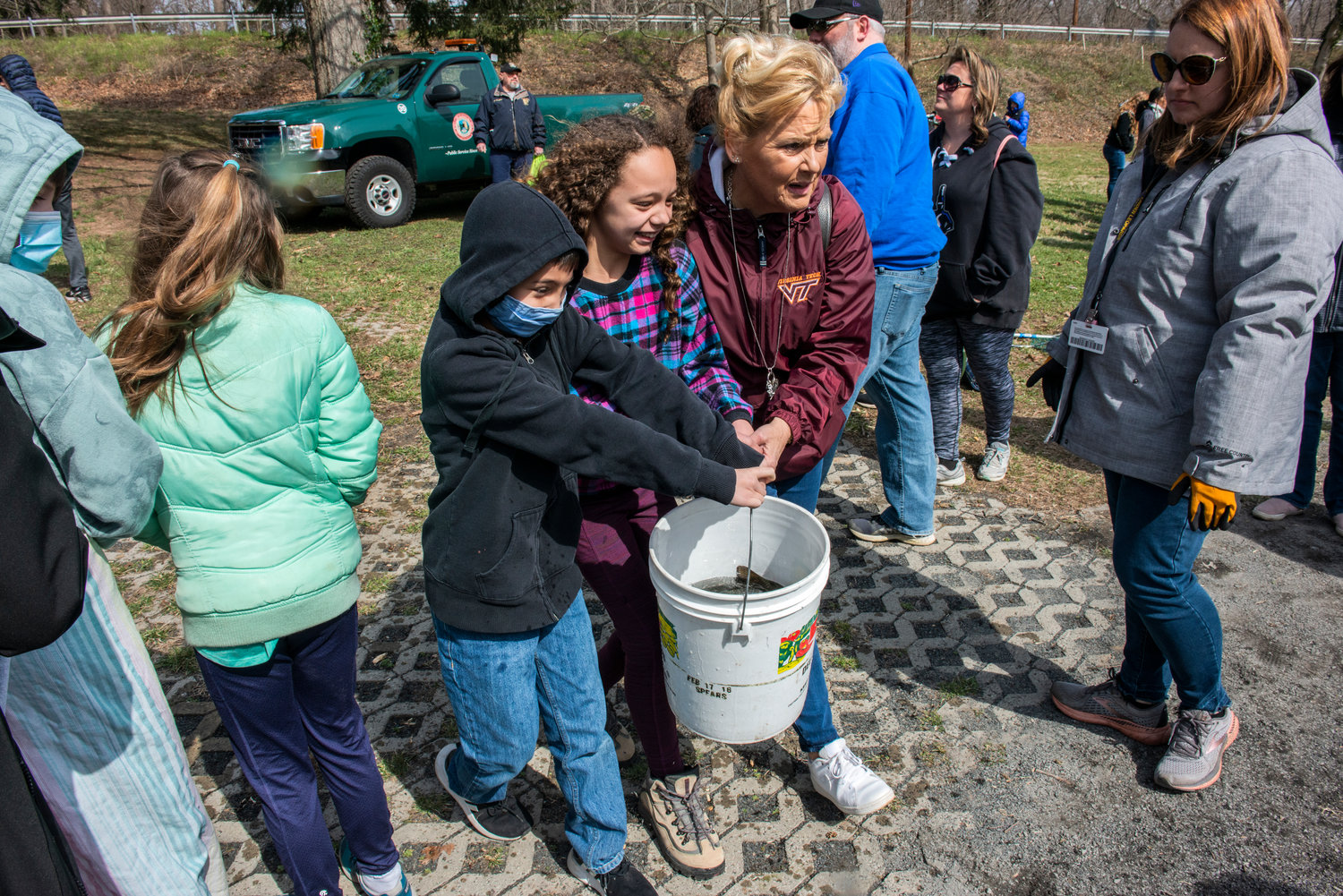 Fifth graders get assistance in carrying fish to the pond.