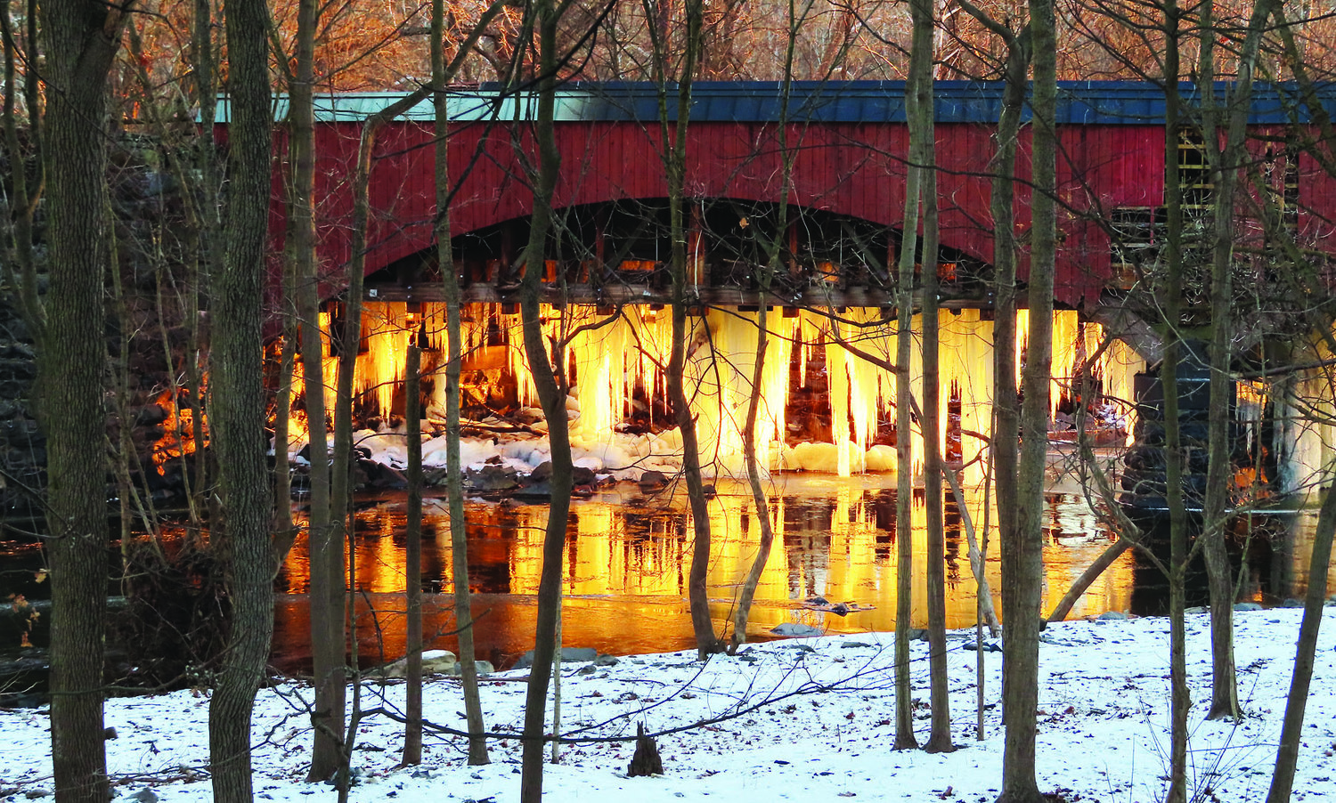 The sun rises over Tohickon Creek at the Point Pleasant Aqueduct on an icy winter morning.