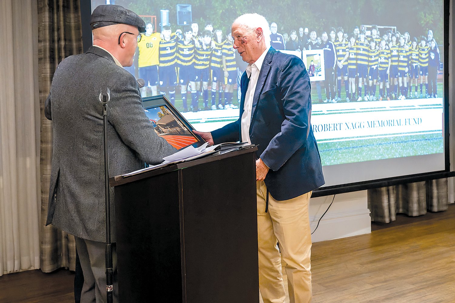 Artist Gordon Haas, left, presents Carl Asplundh Jr. with a giclée of the stadium field house. The co-owner of Asplundh Tree Expert Co. was honored at New Hope-Solebury’s Stadium Soiree in recognition of his donation of $750,000 to the capital fundraising campaign.