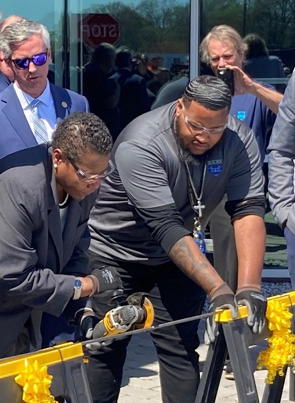 Bucks County Community College President Felicia L. Ganther puts a polish on the traditional ribbon cutting by slicing through a metal rod with a special power saw at the ceremonial unveiling of the college’s new Center for Advanced Technologies in Bristol Township.