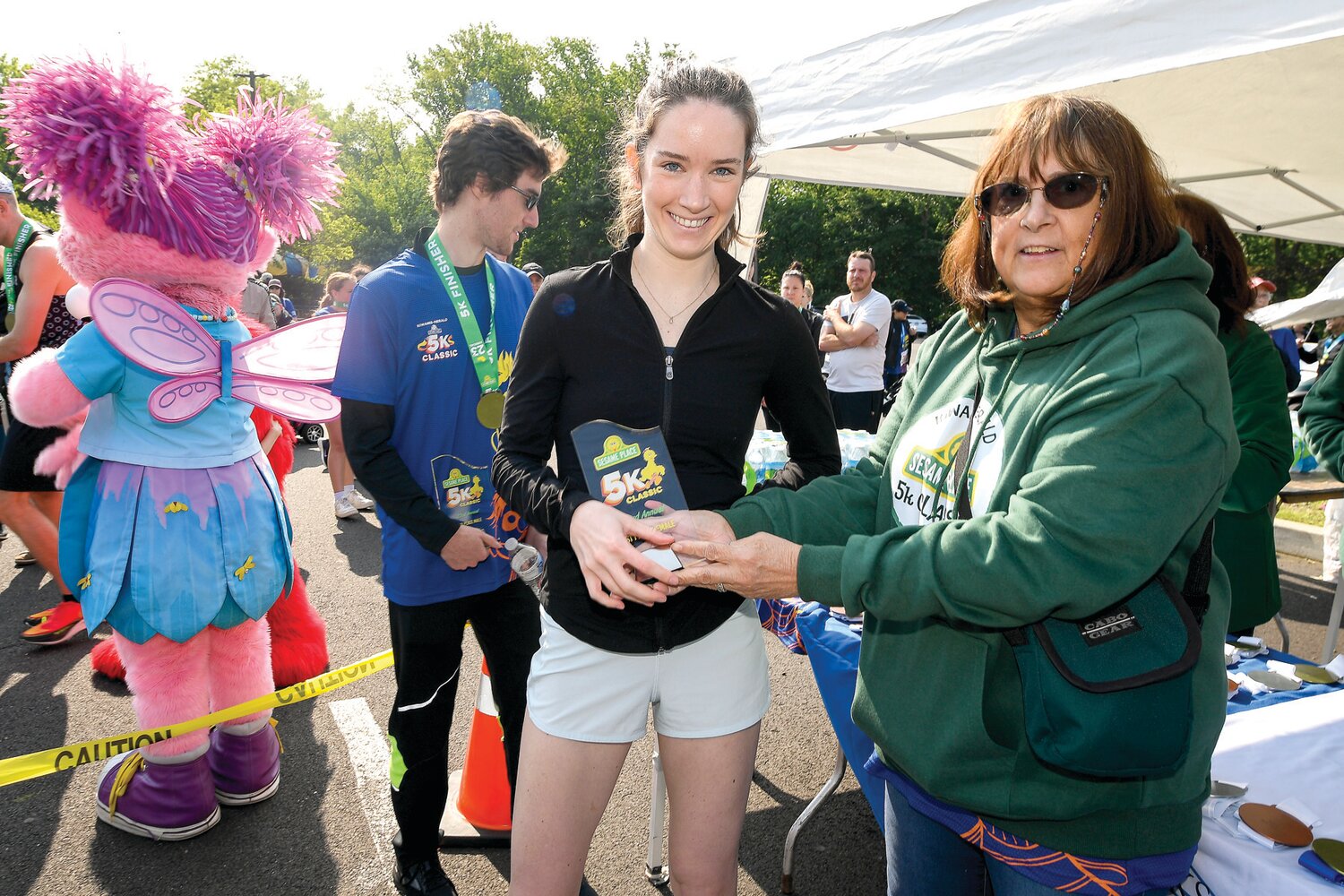 Hannah Malloy of Stamford, Conn., accepts the trophy for the top female finisher in the 5K (18.55).