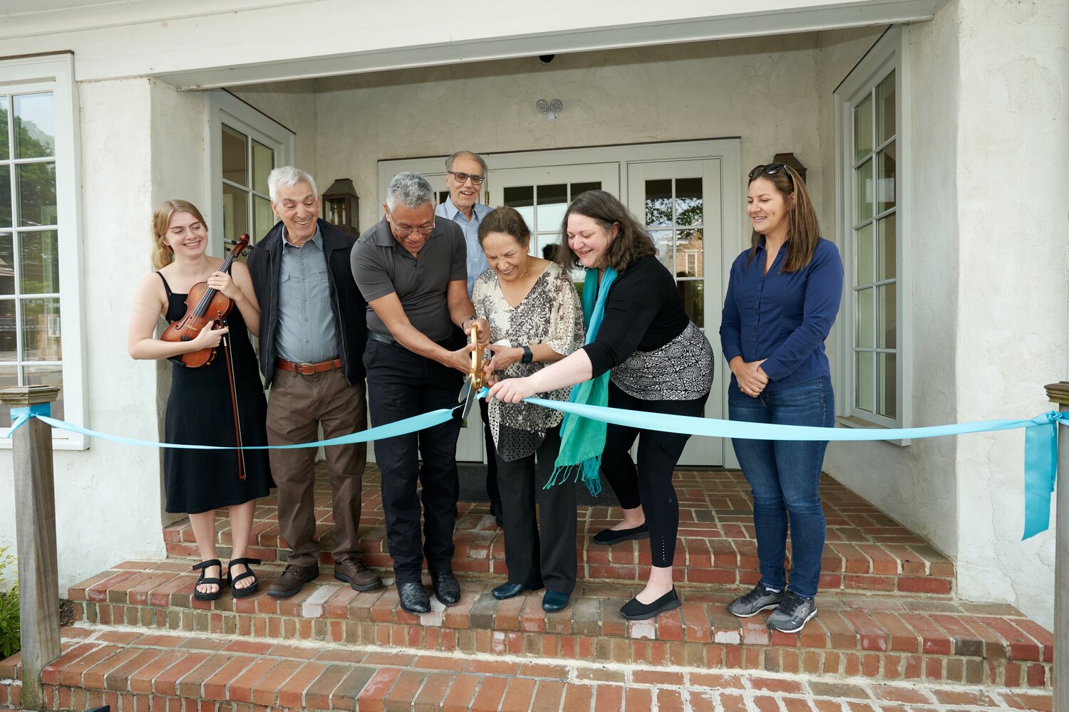 Cutting the ribbon to formally reopen Canal Music Studios in Stockton are, (left to right) Student Coco Brown; Stockton Council President Mike Mann; Greater Princeton Youth Orchestra Board President David DeFreese; Guitar Instructor George Bond; Donor Dr. Rajani Walsh; Canal Music Studios founder Adrienne Walsh; and Jessica Morel, artistic director of Greater Princeton Youth Orchestra.