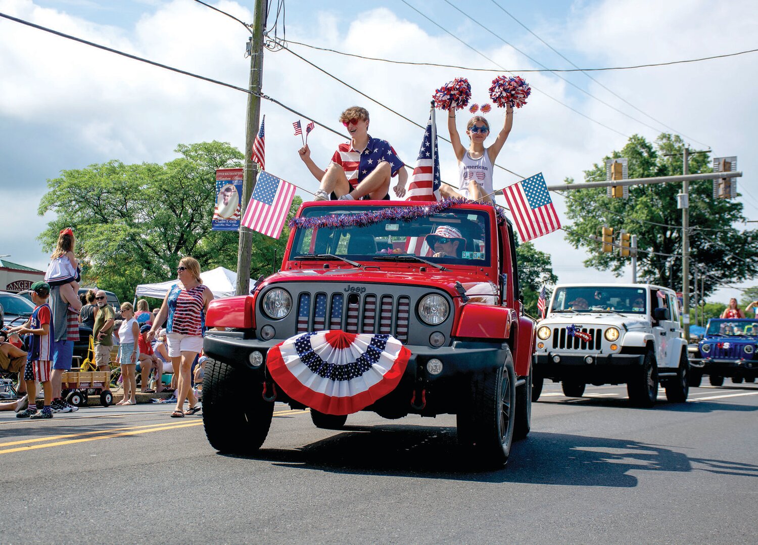 A line of Jeeps drive along the parade route.