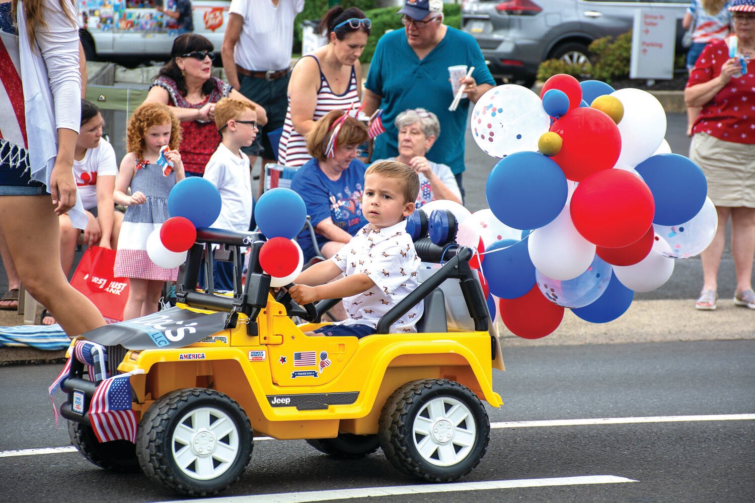 A boy drives his car along the parade route.