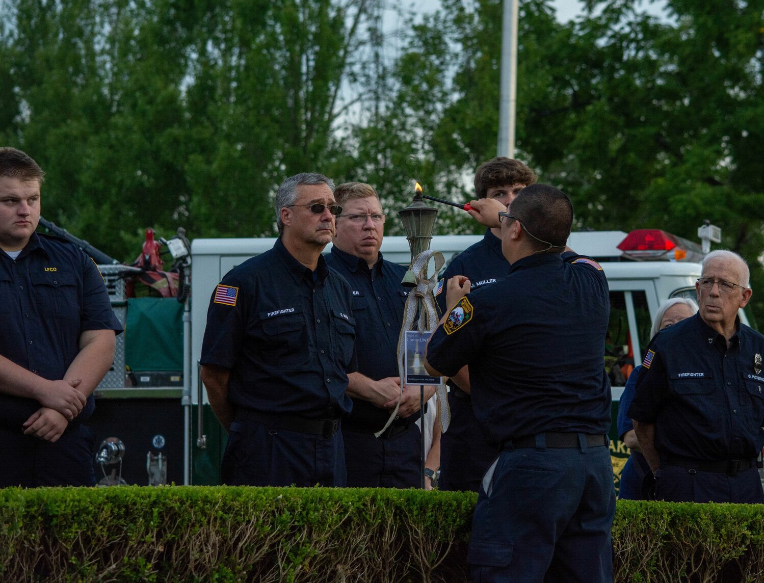 A first responder lights a torch during a ceremony held Sunday at the Garden of Reflection to honor the memory of the victims of the July 15 flash floods.