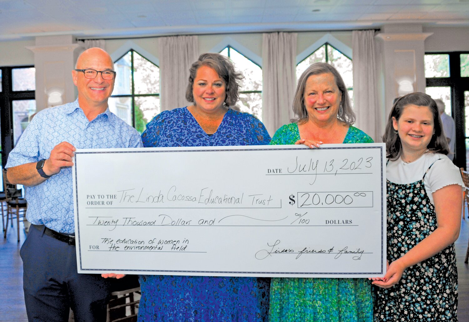 Phil Cacossa, Abigail Robinson, Linda Cacossa and Abigail Robinson hold a check for the Linda Cacossa Educational Trust.