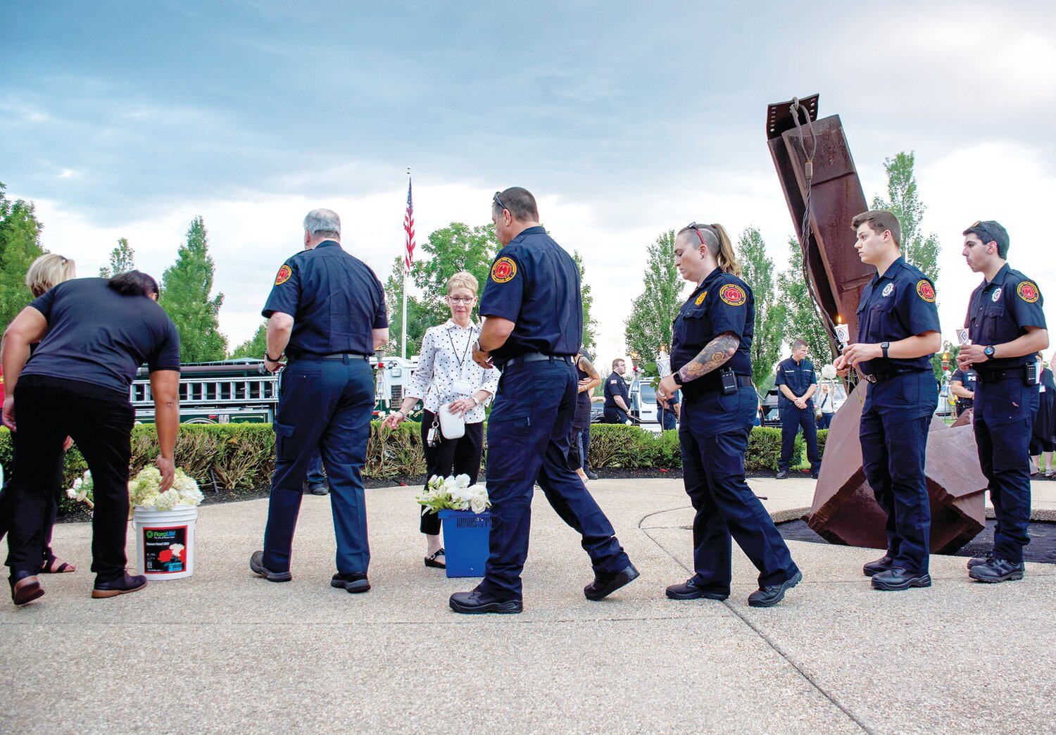 First responders get in line to get flowers to place by victim torches.