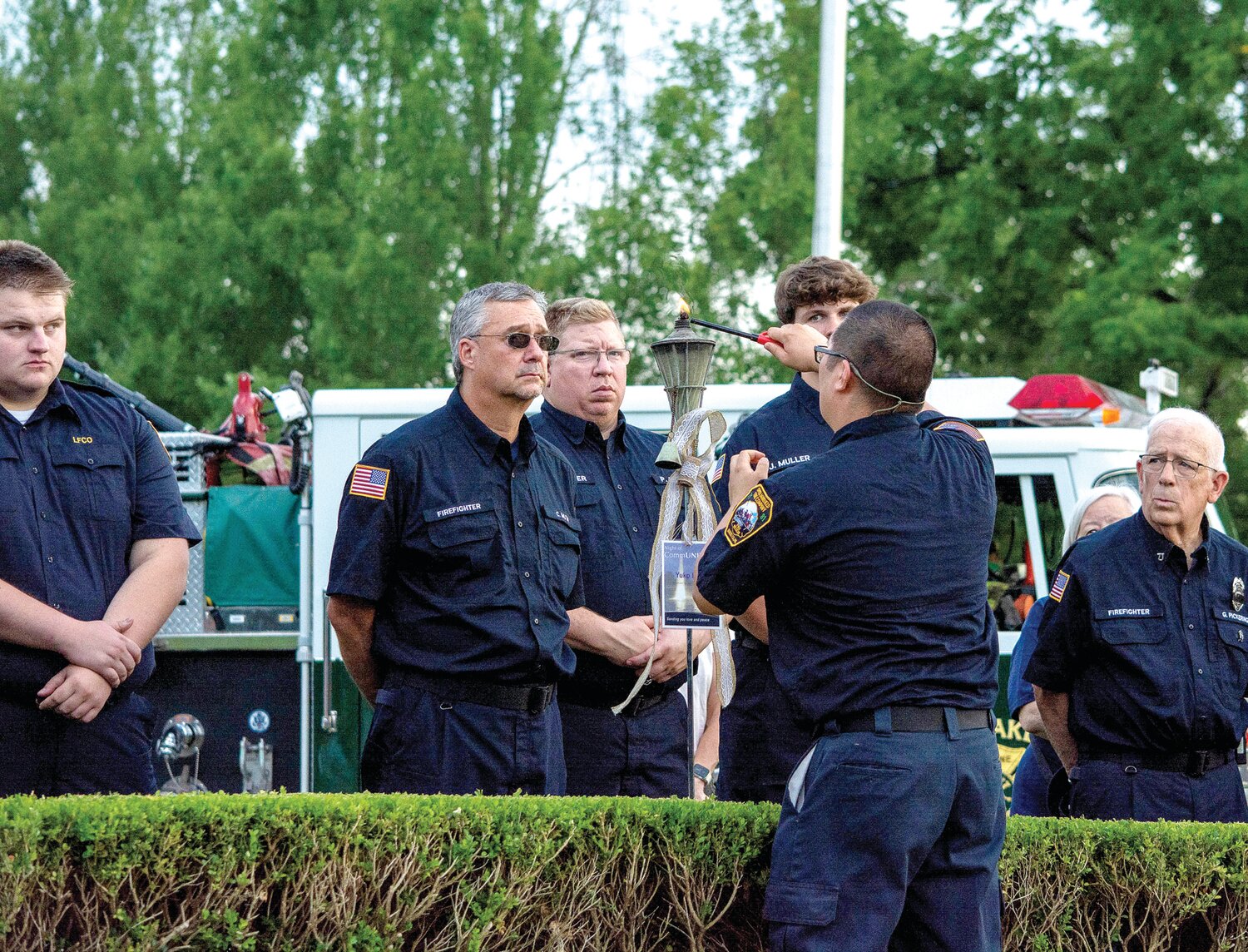 A first responder lights a torch during a ceremony held Sunday at the Garden of Reflection to honor the memory of the victims of the July 15 flash floods.