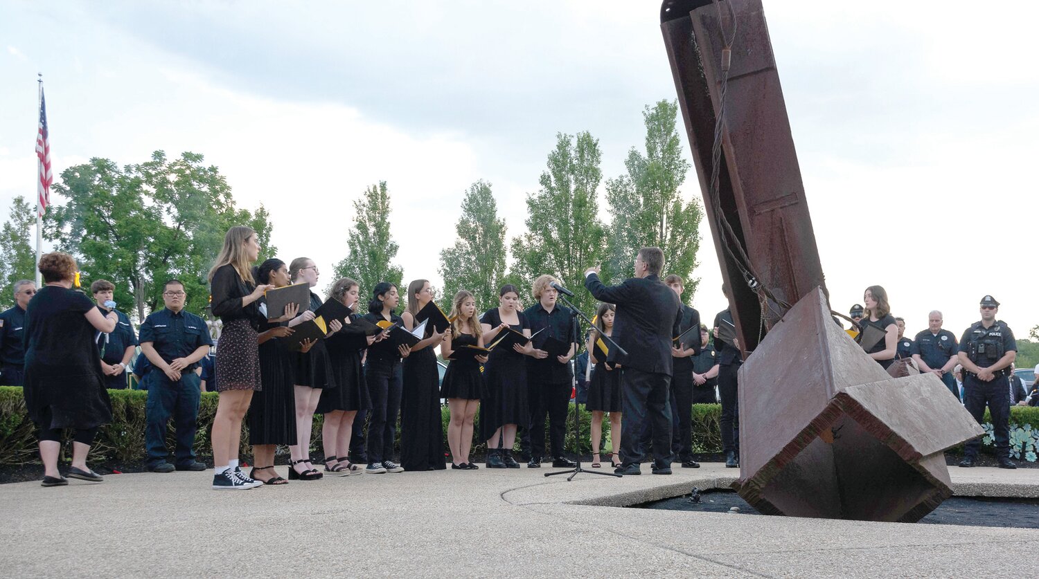 Members of the Council Rock High School South Choir, led by Corey Axler, sing at the vigil.