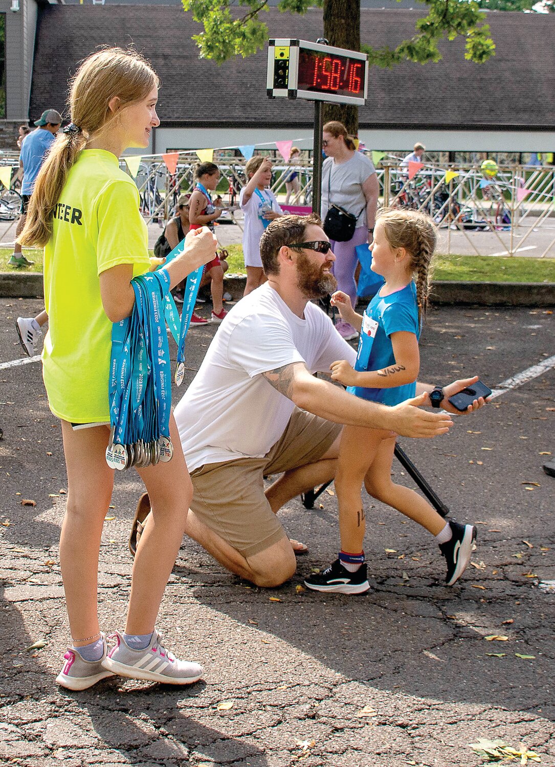 A triathlete gets a congratulatory hug at the finish line.