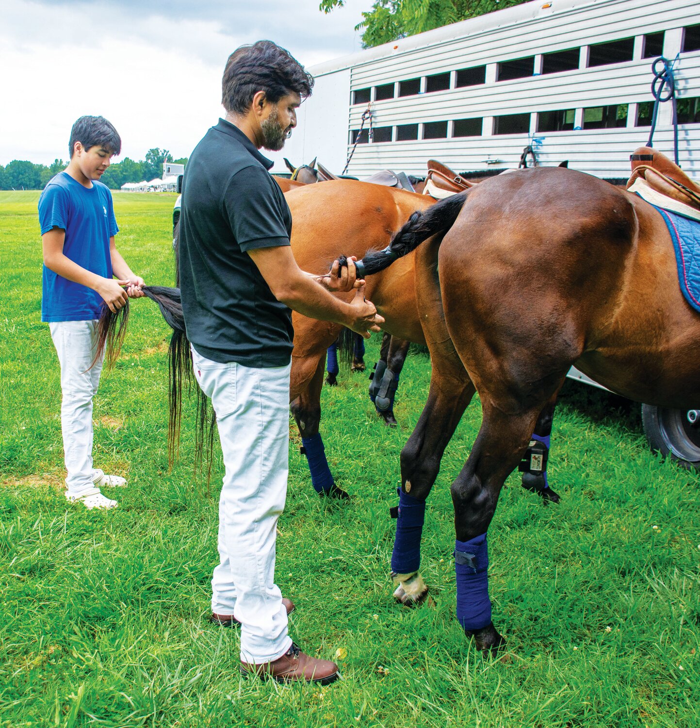 Wind Mill players Talha Chaudhry, foreground, and his son Yusuf, get their ponies ready for the polo match.