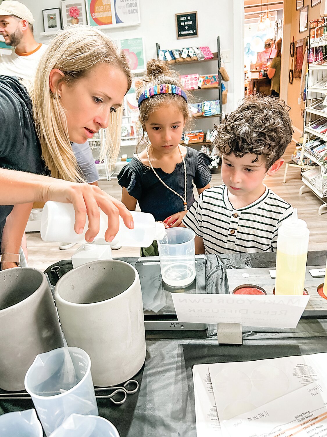 Julie Edelman with Home Again Studios pours materials for young makers taking part in a mini-workshop during an opening event at Makers Off Main.