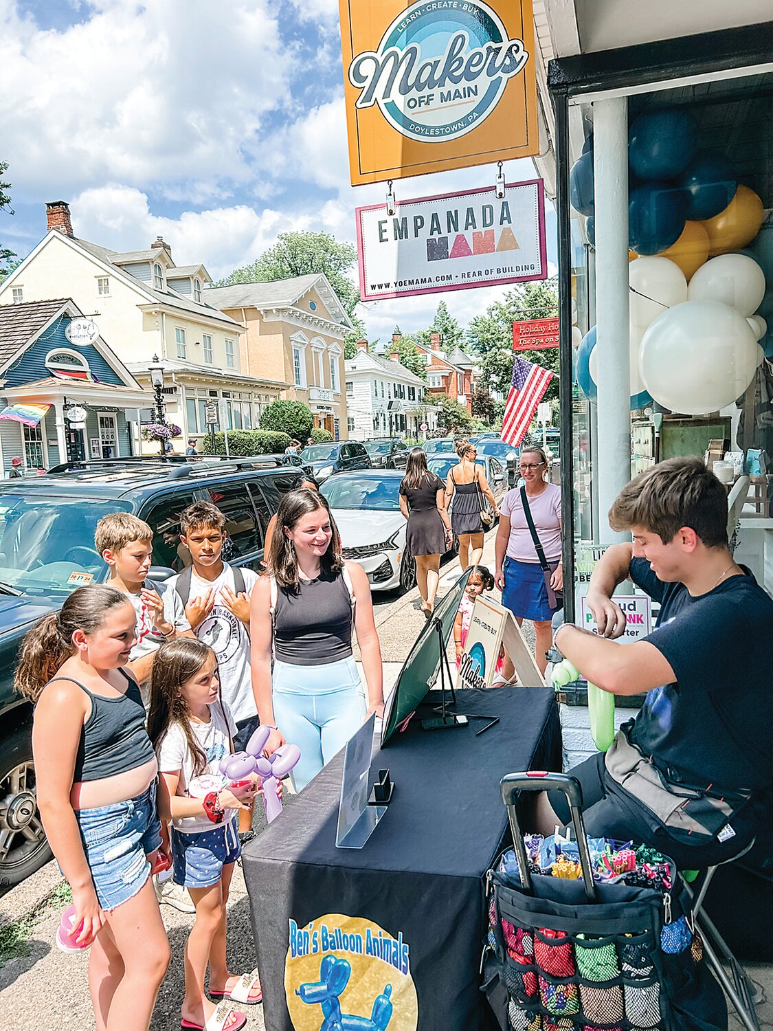 Children watch as a balloon artist creates outside Makers Off Main during an opening event.