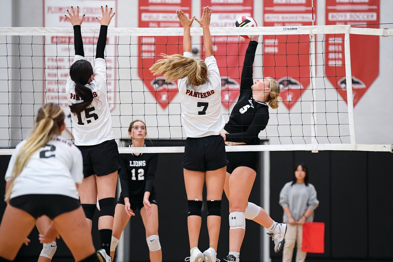 Faith Christian’s Kinsey Reptsik goes for a slam between Plumstead’s Natalie Joseph and Chloe Shackelford.