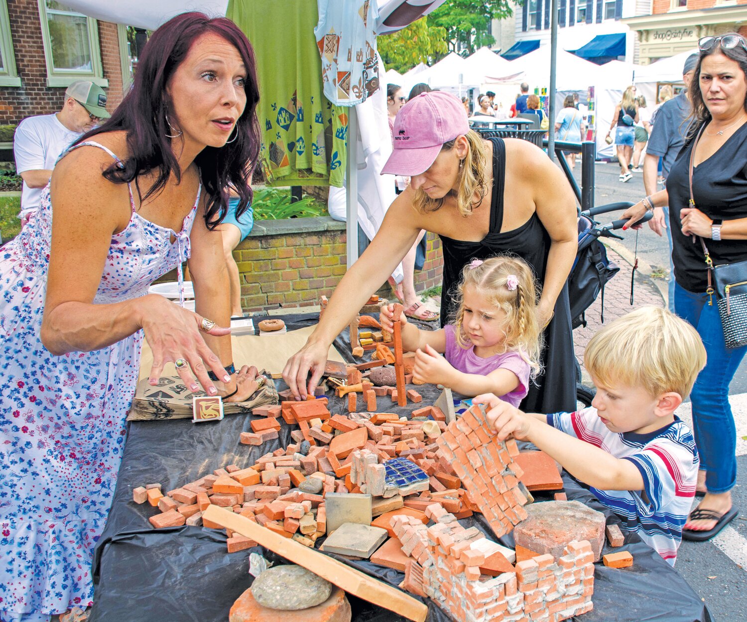 Christie Murphy watches daughter Marianna while Luke Major builds at the Tile Works booth.