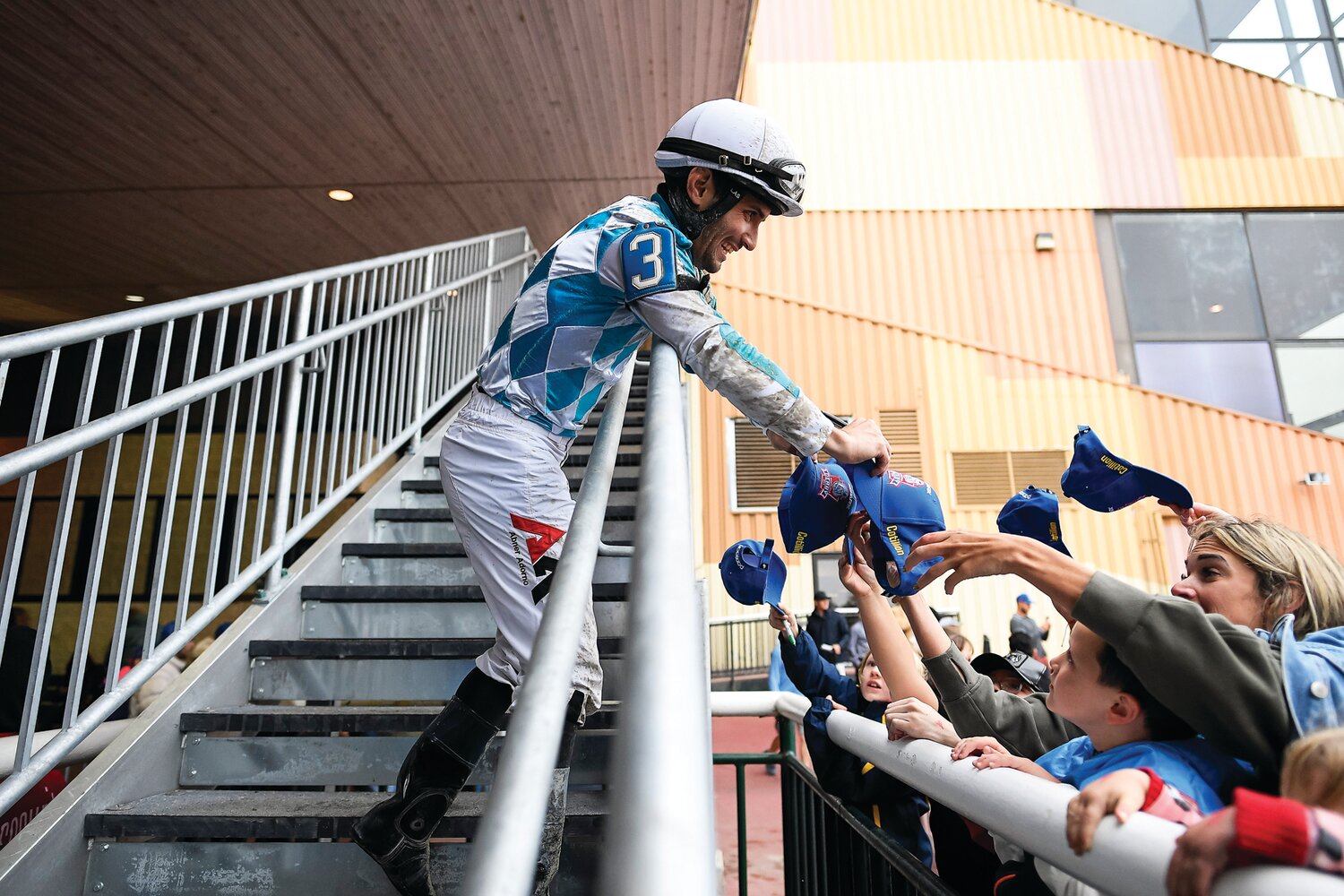 Abner Adorno, jockey of race No. 9 winner King Kumbalay, signs autographs for fans while walking up the steps to the riders’ locker room.