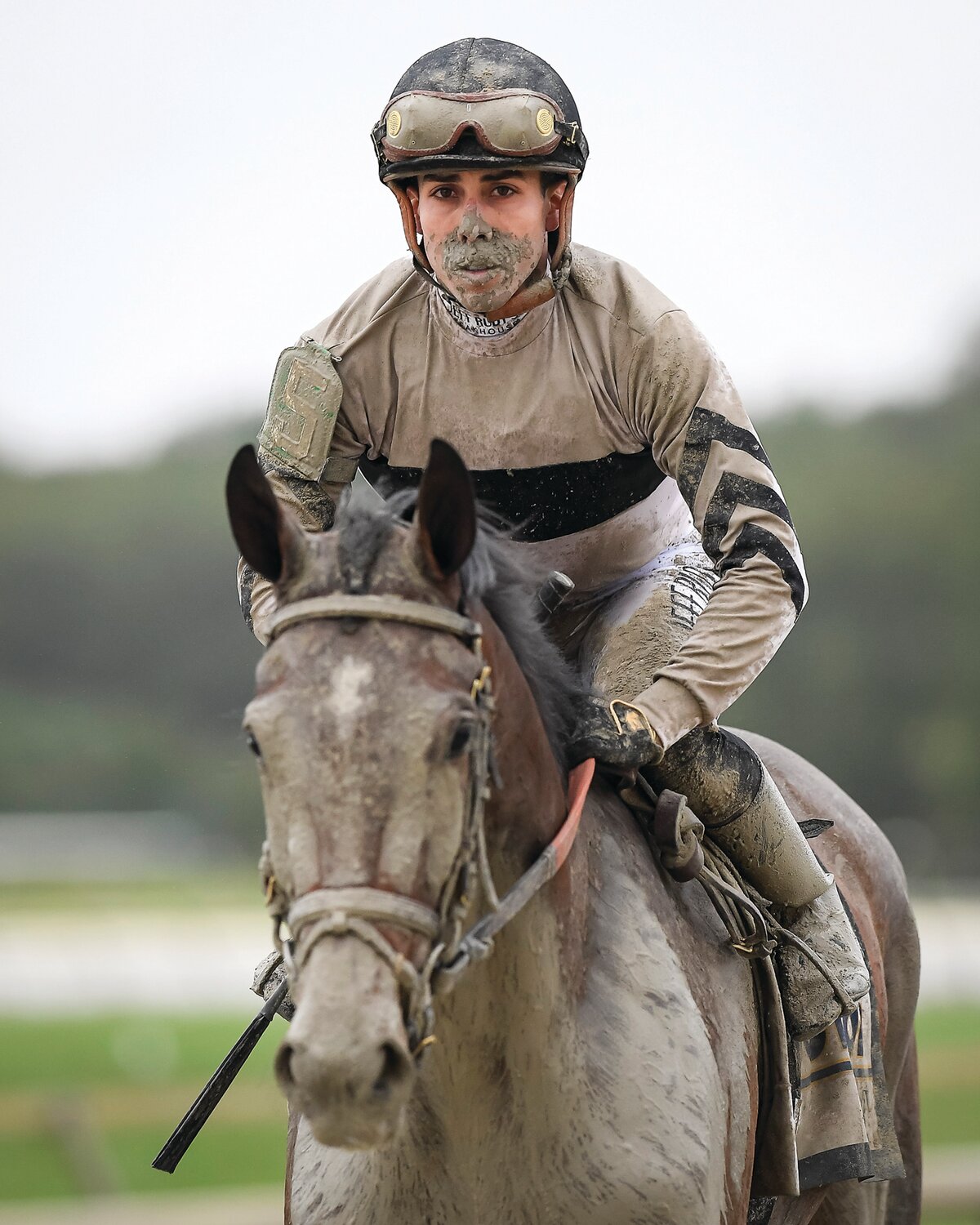 Jockey Irad Ortiz Jr. and Occult are covered with mud after finishing the Cotillion Stakes.