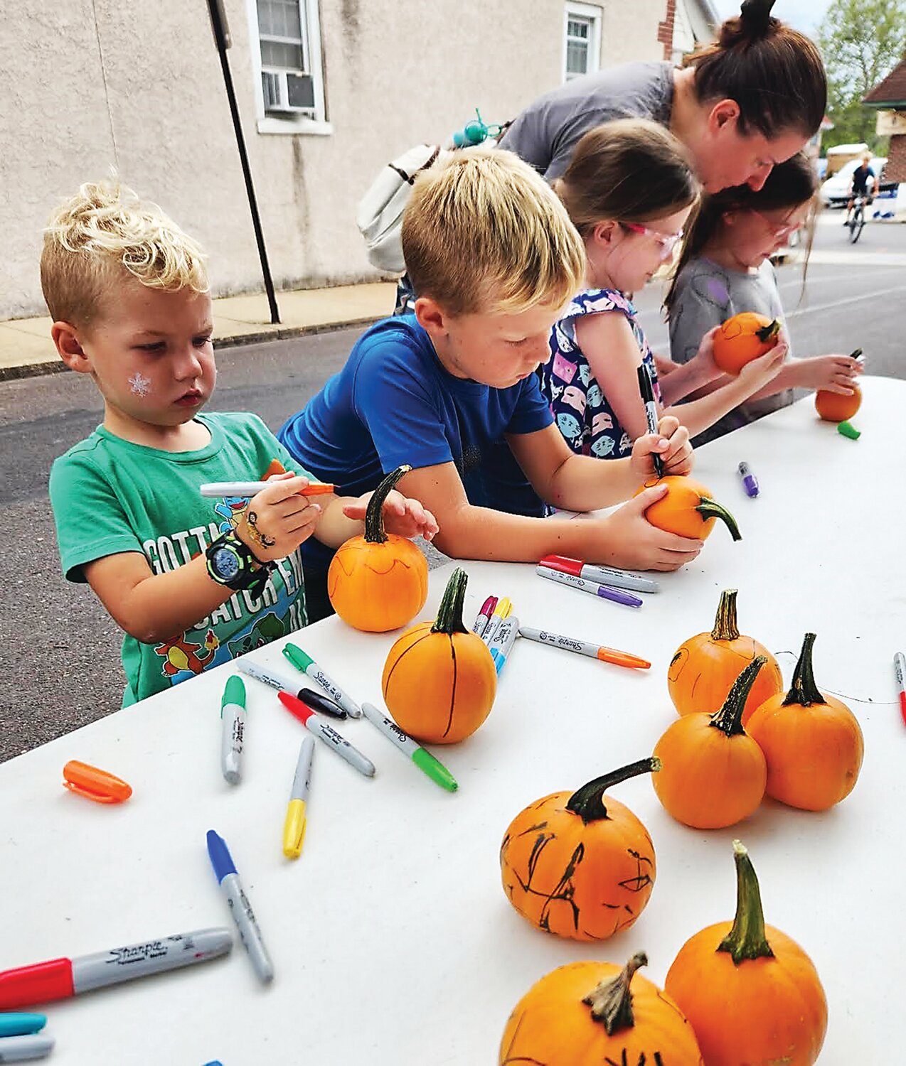 Attendees of the Pennridge Gallery of the Arts event in Sellersville paint pumpkins near Main Street Park.