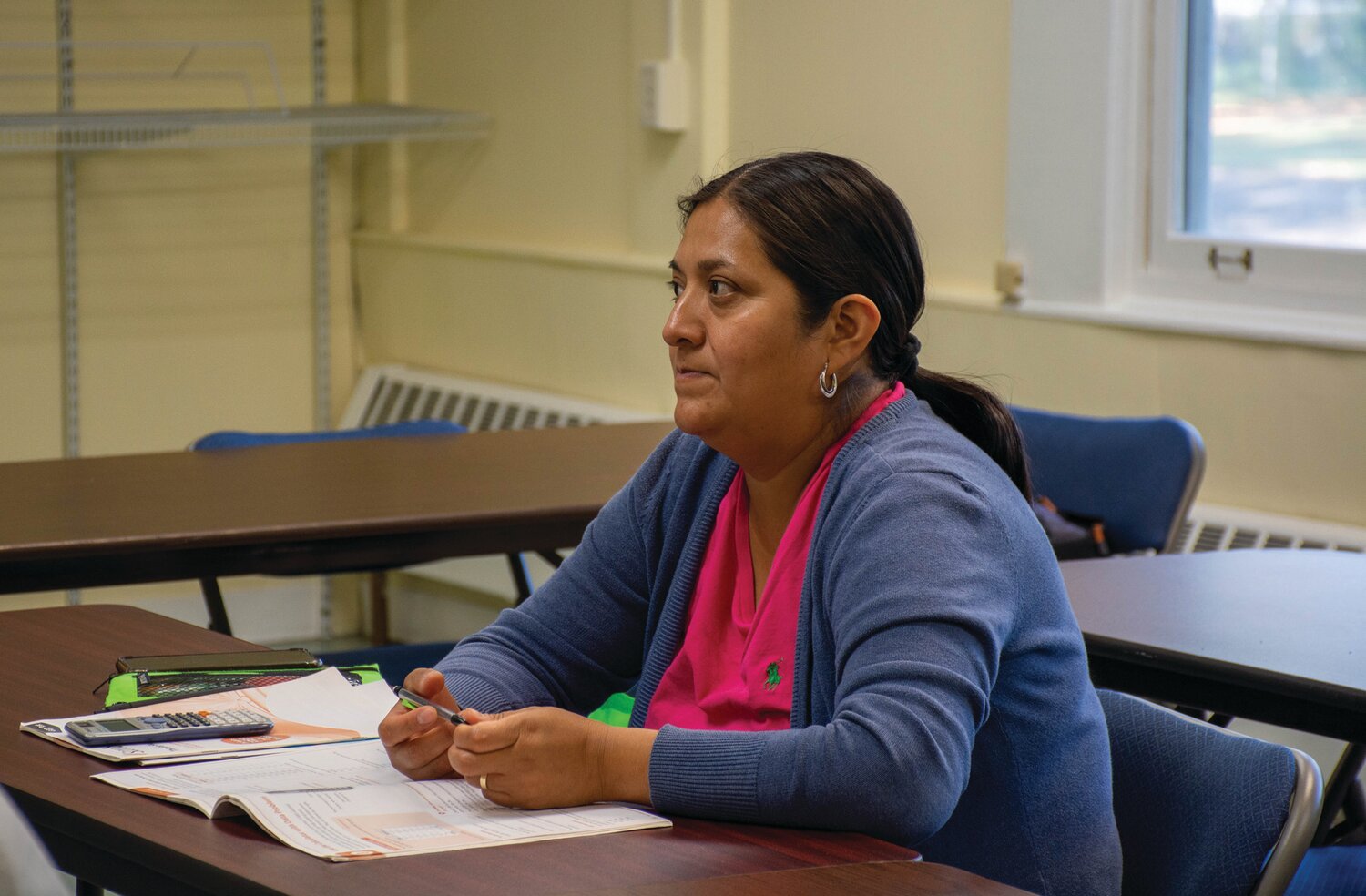 Erika Duran listens as a volunteer with Vita Education Services gives a lesson on the use of calculators to solve data problems.