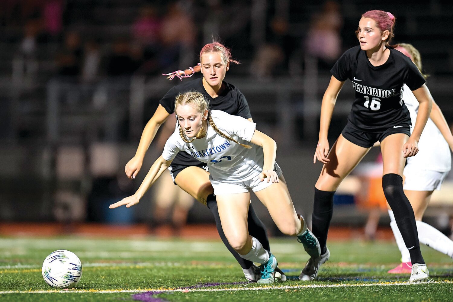 Quakertown’s Rachel McGonagle gets through a double team of Pennridge’s Ava Kiwak, left, and Jesse Moylan, right.