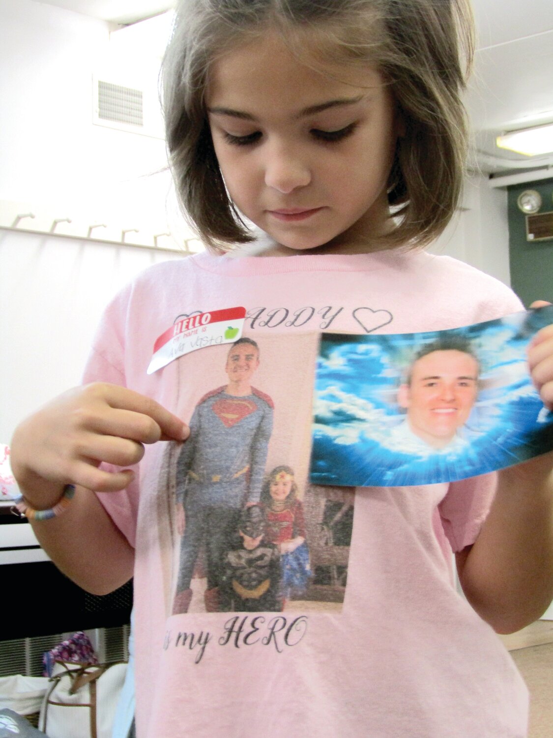 A camper holds a photo of her father, who also appears on a t-shirt she wore to bereavement camp.