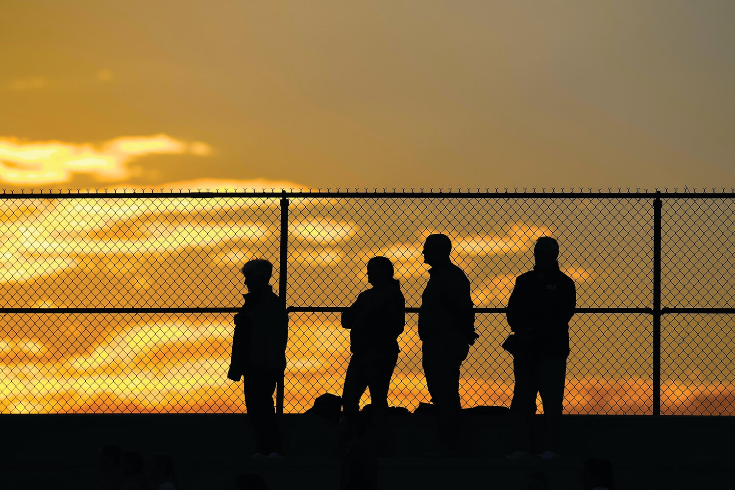 Fans stand during the national anthem as the fall sunset takes over Walt Snyder Stadium.