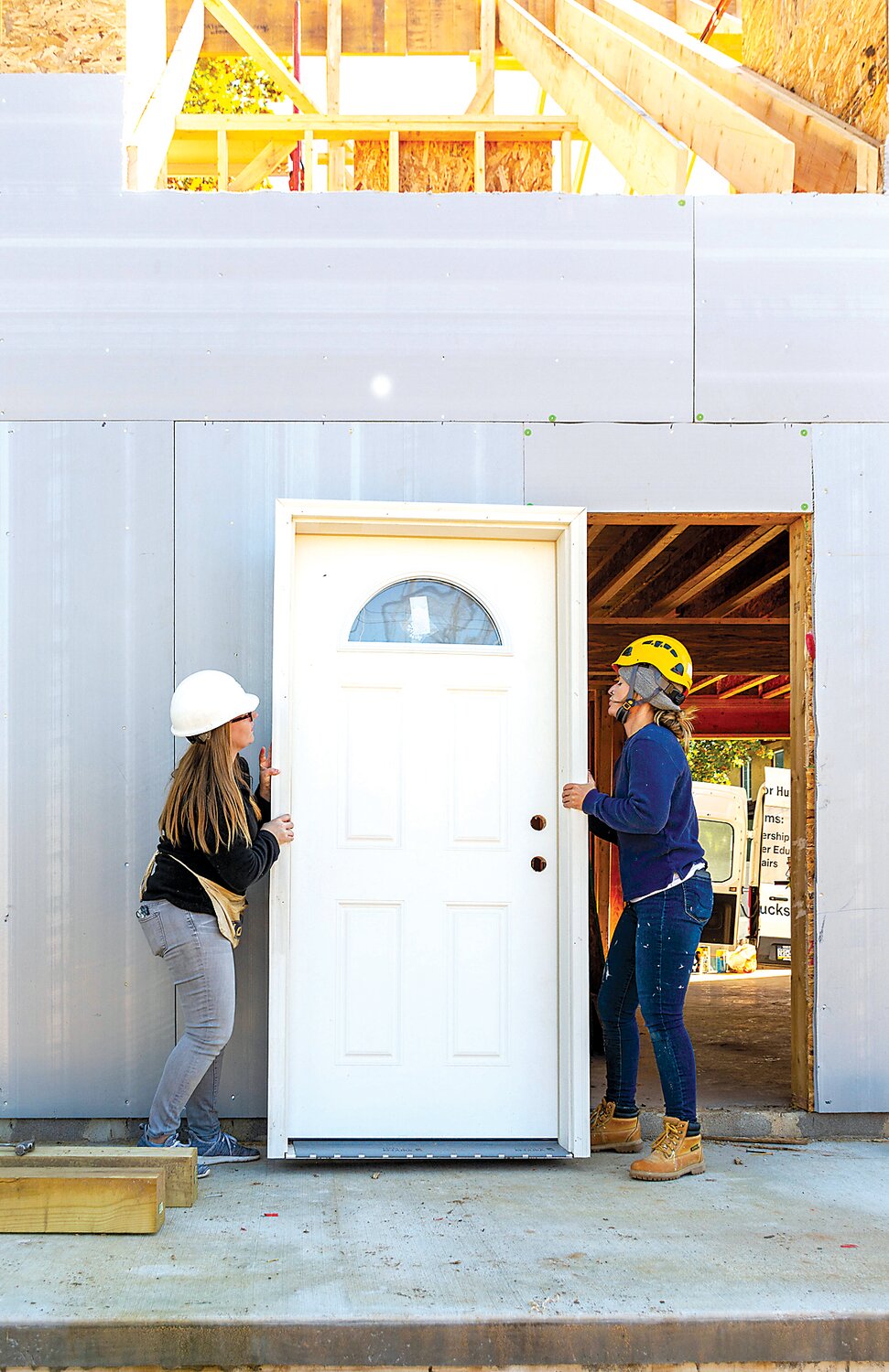 Kristina Van Hart, left, Penn Community Bank, and Katey Smyth, Habitat for Humanity of Bucks County, move a door.