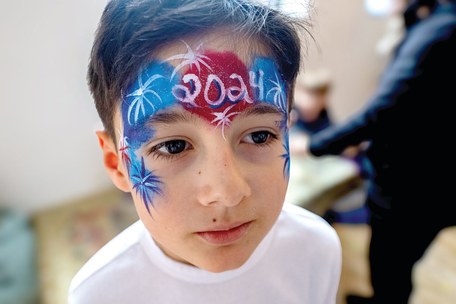 Joseph Zozaya gazes into a mirror to see the painted design on his face.