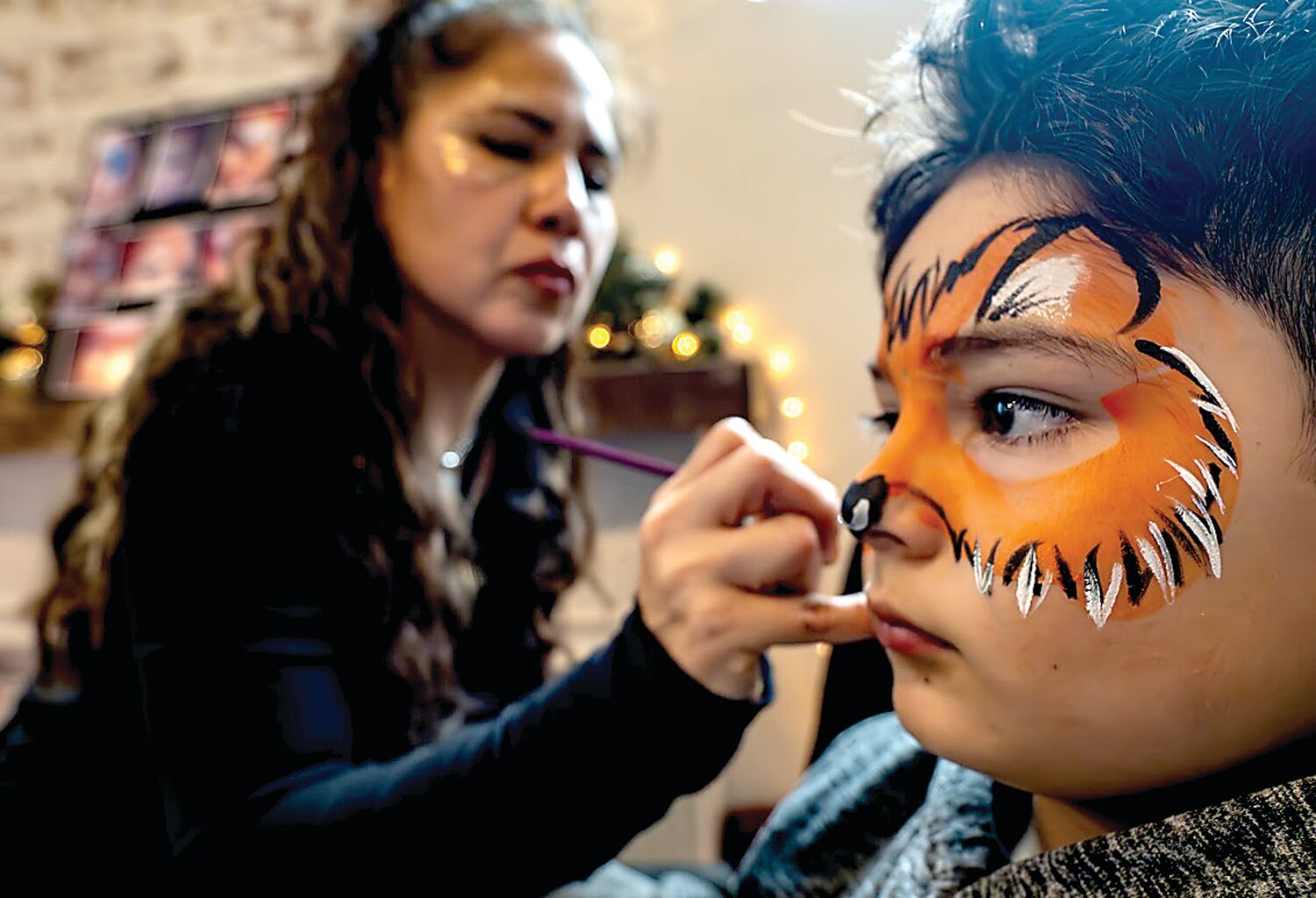 Face painting artist Patty Madrid paints an animal pattern on Julian Zozaya.