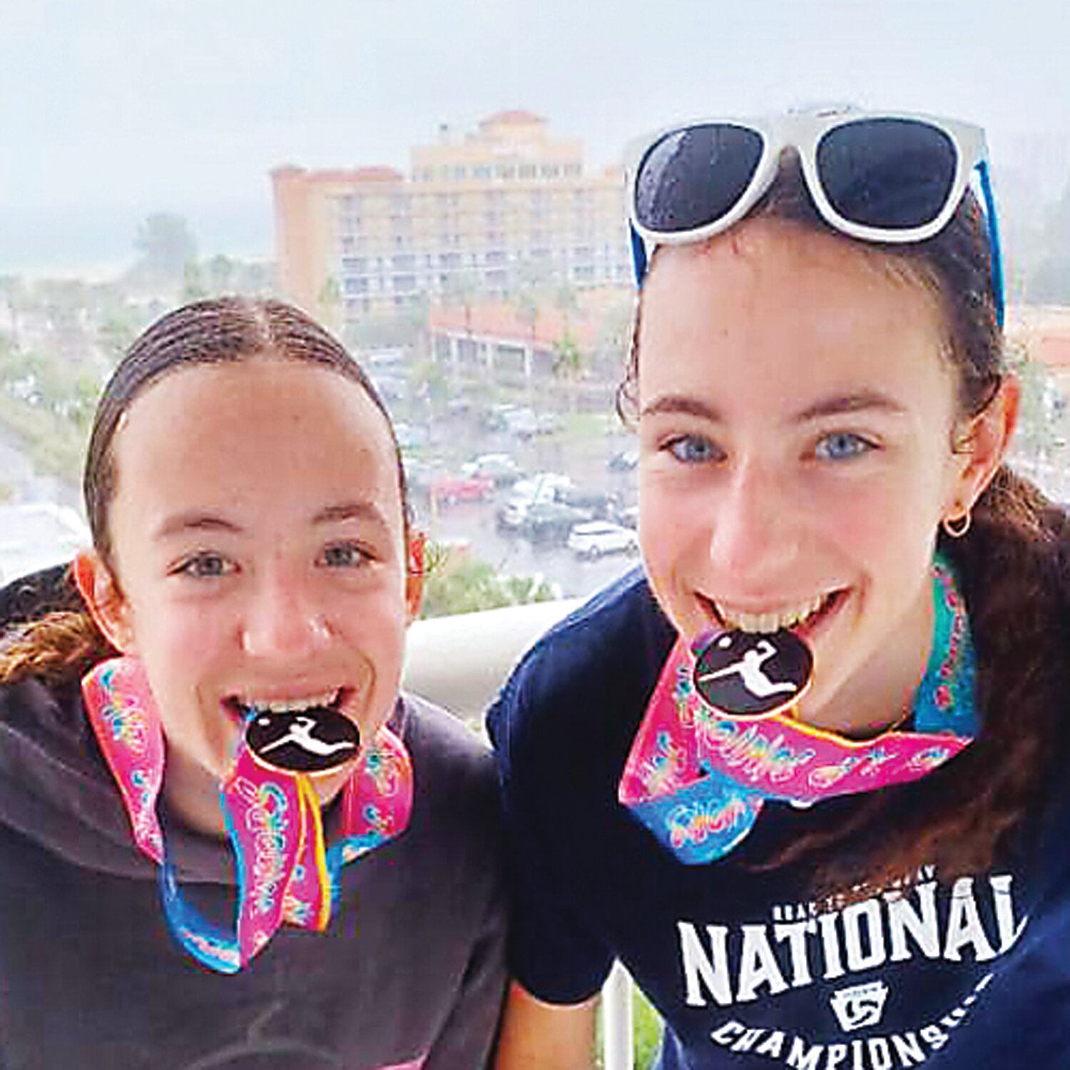 Giuliana Ross and Gabriela Ross bite their medals.