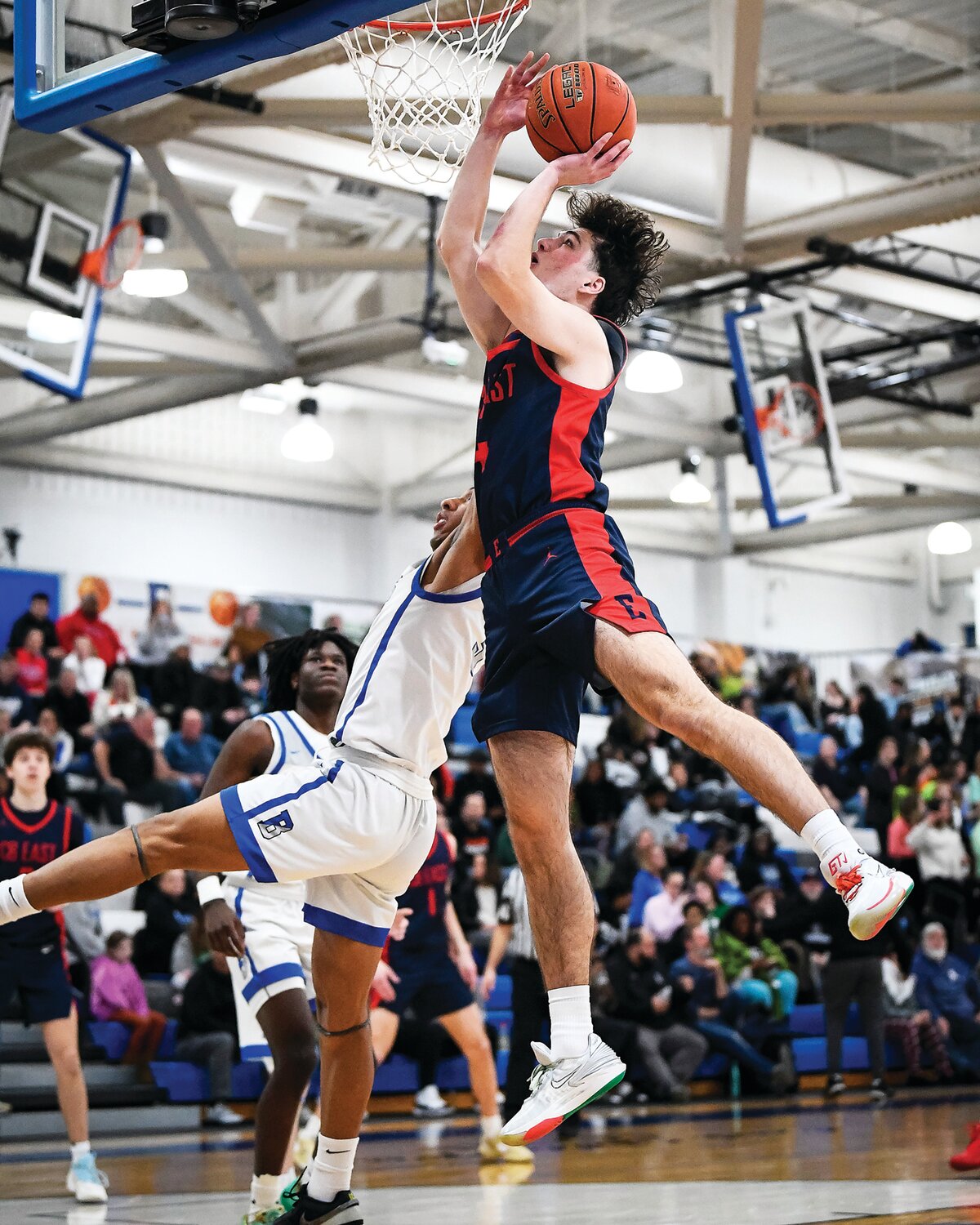 Central Bucks East’s Tyler Dandrea drives to the basket for a layup in front of a slashing  Micah White of Bensalem.