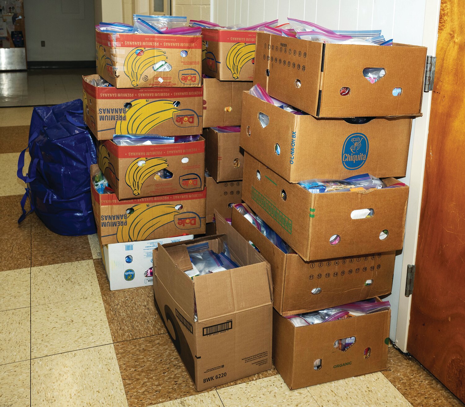 Boxes full of snack bags pile up along the wall of the Our Lady of Grace cafeteria Monday.