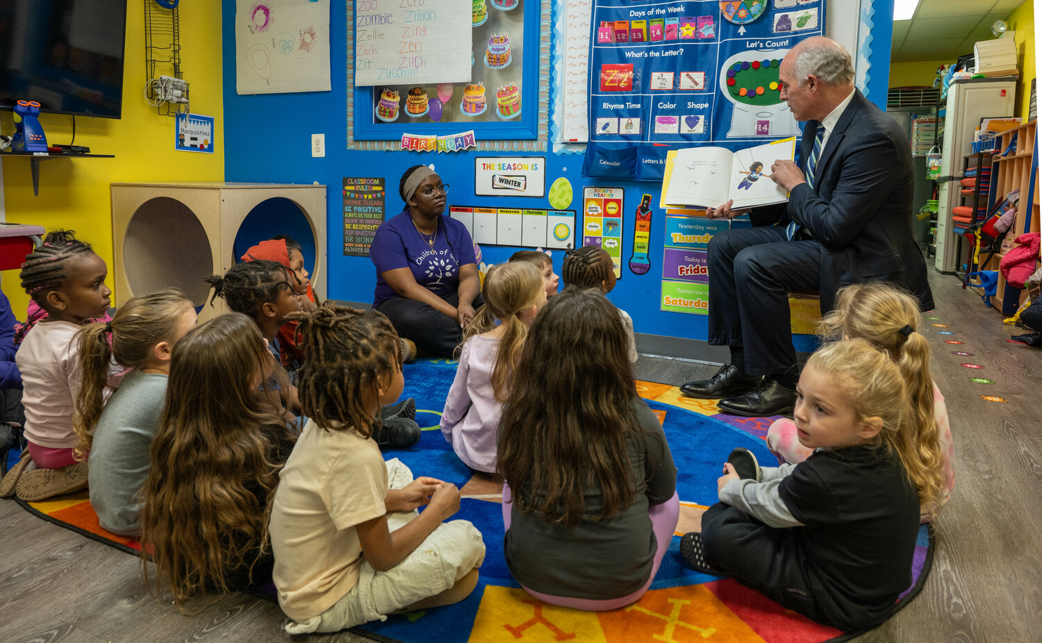 U.S. Sen. Bob Casey reads “I Am Enough” to children as daycare staff member Mandisa Kollie looks on.