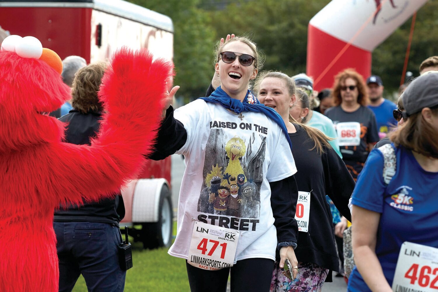 A Sesame Place Classic 5K participant gets a high five from Elmo.