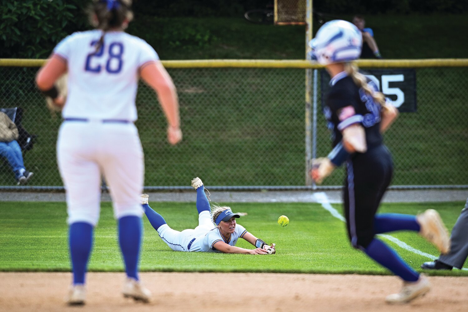 Downingtown West’s Kenzie Anderson’s diving effort comes up just short as Quakertown’s Skyler Williams races to second with a double in last Thursday’s District One 6A final.