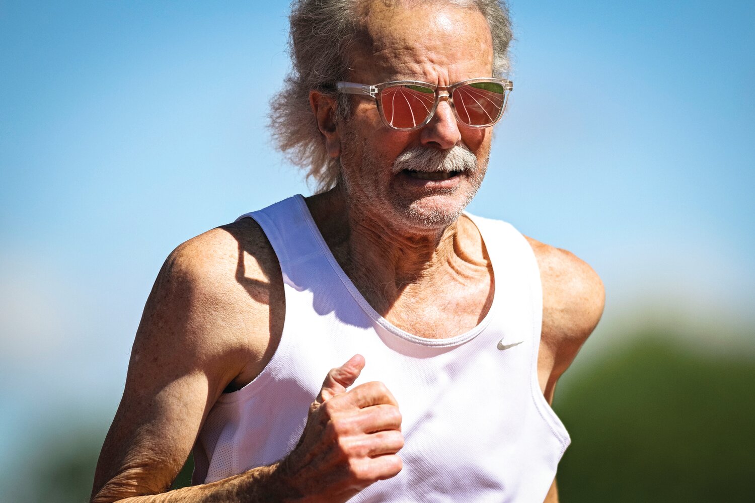 The track reflects off Dave Broadbent’s glasses during the 100-meter run.