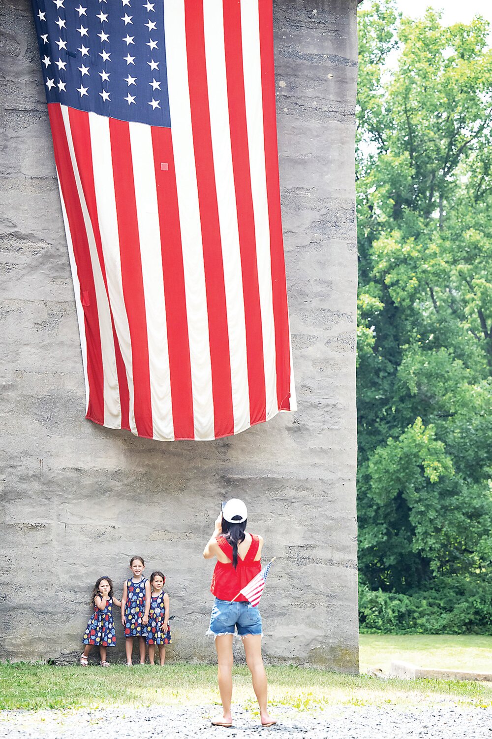 Three girls have their picture taken under an American Flag at Fonthill Castle.