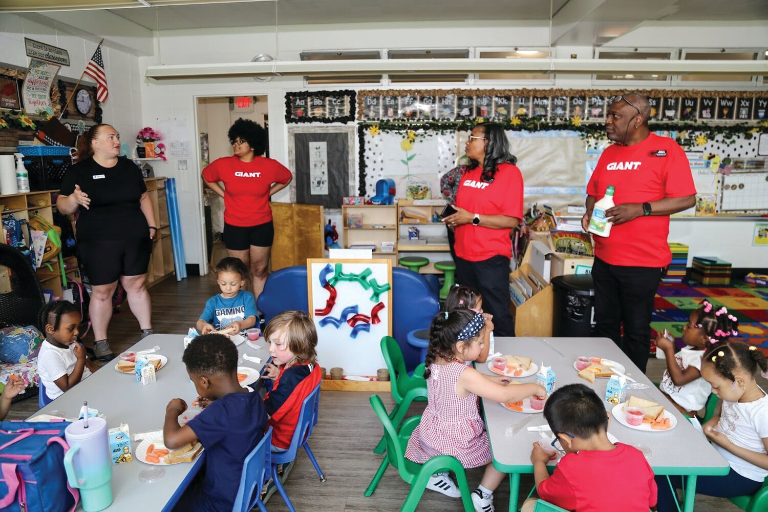 Angela Cloak, director of Pre-K Counts at the Morrisville Child Care Center of River Crossing YMCA, left, works with volunteers from The GIANT Company to distribute milk to students at the center on June 4.