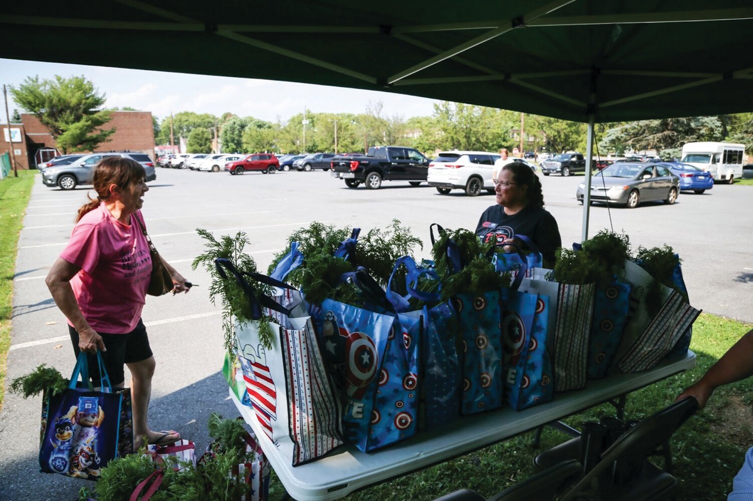 Sheri Moyer, right, volunteer from The GIANT Company, distributes free bags of fresh produce to community members outside the Bethlehem branch of River Crossing YMCA on July 16.