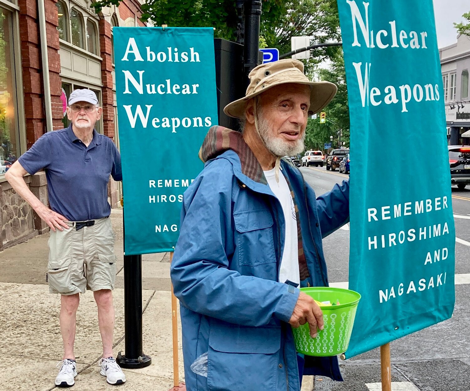 Ken Johnson and Alan Stifelman carry banners during Tuesday’s vigil at State and Main streets.