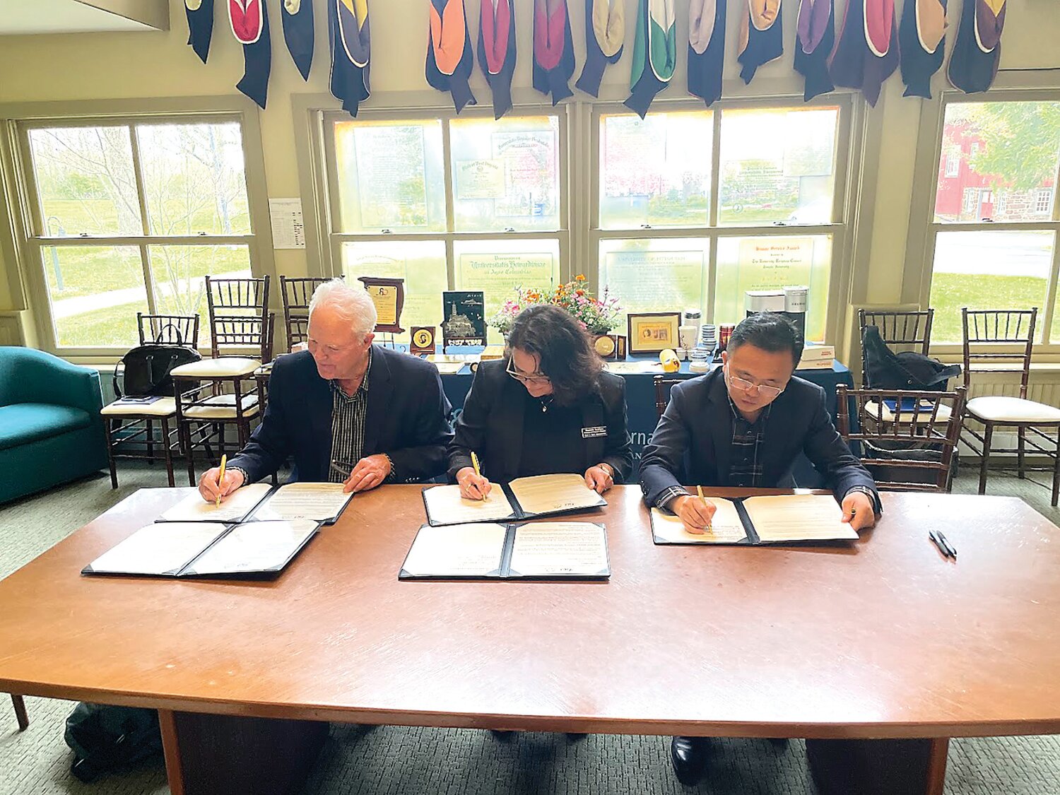 Steve Harnsberger, founder of PPX in San Francisco; Stephanie Saveriano, international programs director for Pearl S. Buck International; and Yuan Yong, deputy mayor of Lushan City, China, sign a memorandum of agreement for a museum and cultural exchange program.