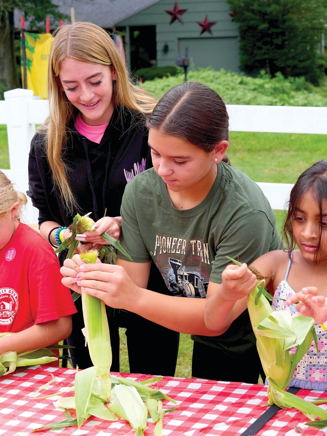 Children participate in a corn husking competition during Charlann Farms’ Sweet Corn Festival Aug. 4.