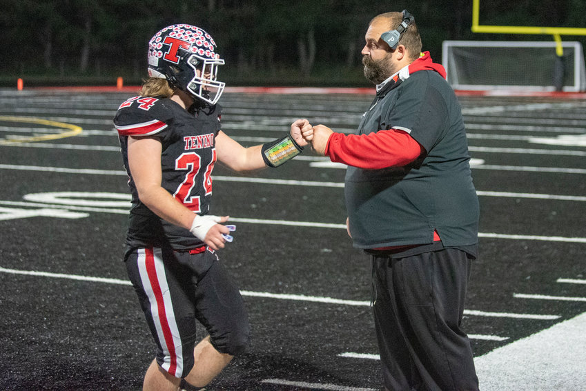 Tenino senior Shawn Nicholson (24) fist bumps head coach Cary Nagel during a playoff game against Castle Rock on Friday, Nov. 5, 2021.
