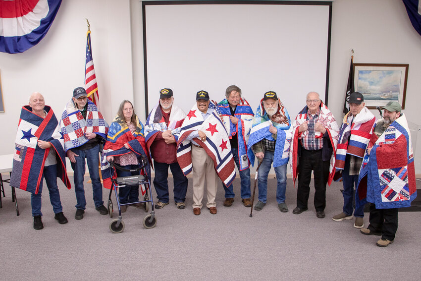 From left to right, veterans Ken Paulson, Jens &ldquo;Tony&rdquo;  Thompson, Doreen Schweikl, Ruben Segovia, Brando Skanes, Billy Clark, William &ldquo;Bill&rdquo; Murdock, Erle Cooper, Robert Heaney and Curtis Steffen stand with their new handmade quilts wrapped around their shoulders at the Veterans Memorial Museum.