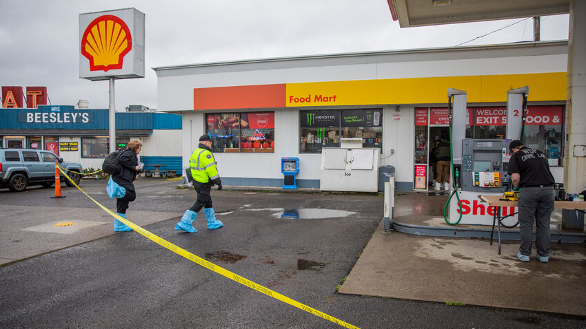 Authorities from the sheriff's office, coroner's office and the Washington State Patrol process the scene of a robbery and murder at a Toledo area Shell station on Thursday.