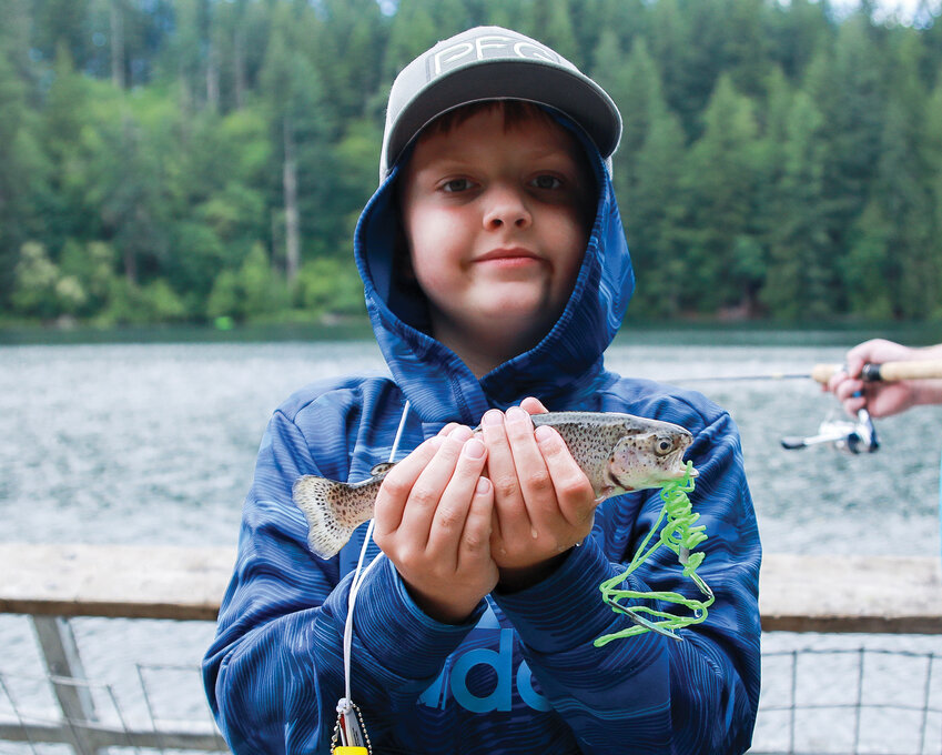 Landon Uhacz holds up a trout he caught earlier in the day at Battle Ground Lake State Park during the Columbia Springs&rsquo; fishing celebration on Saturday, June 10