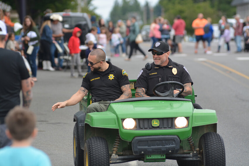 Thurston County Sheriff Derek Sanders, left, and Yelm Police Chief Rob Carlson smile and wave to spectators at the Prairie Days Parade on June 24.