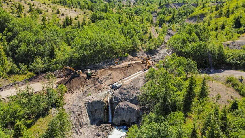 Crews are seen from above late last month as pipes are placed and dirt is moved to create a traversable path along Spirit Lake Highway following a landslide in May.