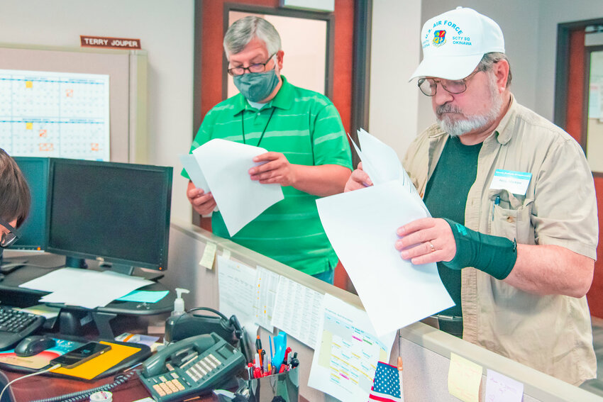 FILE PHOTO &mdash; Democrat Precinct Committee Officer Neil Marsh checks papers with Chief Deputy Auditor Tom Stanton during the logic and accuracy test certification process at the Lewis County Courthouse in July 2021.