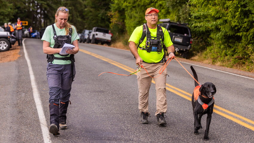 Chris Terpstra, center, a founding member of Cascadia Search Dogs, walks along the 100 block of Black Bear Lane in Centralia on Tuesday while looking for evidence of Martha Norman, a missing 92-year-old woman with dementia who is believed to be in danger.